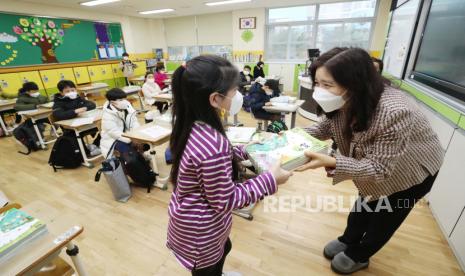  Seorang guru memberikan buku pelajaran kepada siswanya di sebuah sekolah dasar di Sejong, Korea Selatan, 02 Maret 2021. Sekolah-sekolah di seluruh negeri dibuka kembali di tengah pandemi virus Corona yang sedang berlangsung.