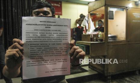 Pemerintah Kabupaten Karawang menerapkan pembatasan aktivitas pasa jam malam. Kebijakan ini menyusul meningkatnya penyebaran Covid-19 di Kota tersebut.Ilustrasi pedagang menunjukkan lembaran sosialisasi pembatasan jam malam di margonda, Depok, Jawa Barat, Senin (31/8/2020). 