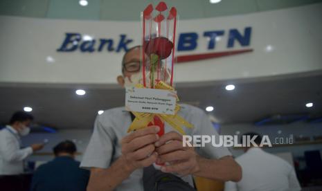 Nasabah  Bank BTN menunjukan bunga yang diberikan saat peringatan hari pelanggan di Kantor Cabang Jakarta Harmoni. PT Bank Tabungan Negara (Persero) Tbk optimistis akan memenangkan ketatnya persaingan digital banking dalam industri perbankan Tanah Air. Melalui proses transformasi digital yang sedang mereka persiapkan, BTN akan menjelma menjadi bank terbaik segmen pembiayaan perumahan atau best mortgage bank di tingkat Asia Tenggara.