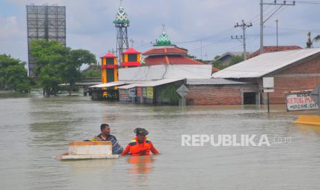 Warga melintasi jalan Pantura yang terendam banjir di Karanganyar, Demak, Jawa Tengah, Ahad (17/3/2024). Banjir yang disebabkan jebolnya tanggul Sungai Wulan pascahujan deras dari wilayah hulu itu merendam jalan nasional jalur Semarang-Surabaya, sementara arus lalu-lintas dialihkan ke jalur alternatif melalui Kabupaten Jepara dan Grobogan. 