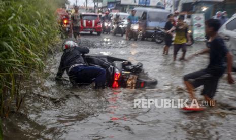 Pengendara sepeda motor terjatuh saat melintasi Jalan Raya Bojong Gede-Citayam yang banjir di Bojong Gede, Kabupaten Bogor, Jawa Barat, Selasa (15/9/2020). Salah satu akses jalan menuju kawasan Pemerintahan Kabupaten Bogor dan stasiun kereta tersebut rusak dan berlubang sehingga digenangi air sehabis hujan sehingga membahayakan bagi pengendara dan menyebabkan kemacetan. 