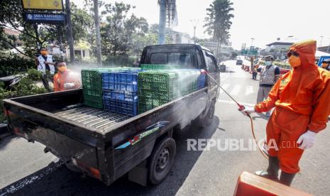 Petugas Dinas Kesehatan Kabupaten Bogor menyemprotkan  disinfektan ke mobil yang melintas di jalur wisata Puncak, Kabupaten Bogor, Jawa Barat, Sabtu (4/4). Kegiatan tersebut sebagai antisipasi pencegahan penyebaran COVID-19 di kawasan wisata Puncak Bogor