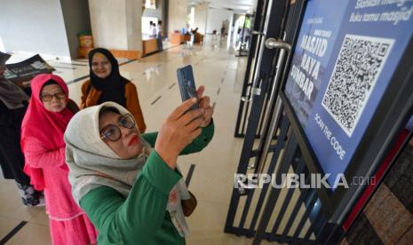 Pengunjung memindai QR code untuk mengisi buku tamu di Masjid Raya Sumatera Barat di Padang, Senin (27/3/2023). Masjid Raya Sumatera Barat bekerja sama dengan Dinas Komunikasi Informatika dan Statistik (Diskominfotik) Sumbar dalam melakukan digitalisasi terhadap pelayanan di masjid tersebut, di antaranya pengisian buku tamu, survei, pembayaran infak dan informasi masjid melalui QR Code serta pelayanan wifi gratis bagi pengunjung. 