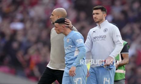 Pelatih kepala Manchester City Pep Guardiola, dan pemain Phil Foden dan Aymeric Laporte, dari kiri, berjalan di lapangan pada akhir pertandingan sepak bola semifinal Piala FA Inggris antara Manchester City dan Liverpool di stadion Wembley di London, Sabtu, 16 April 2022 Liverpool menang 3-2.