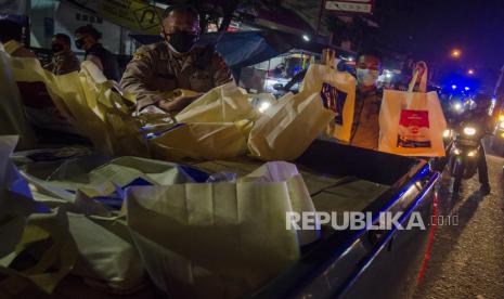 Anggota Kepolisian mengambil sejumlah paket bantuan sosial sembako untuk dibagikan kepada warga di Bandung, Jawa Barat, Jumat  (23/7/2021) malam. Sedikitnya 500 paket bansos sembako diberikan oleh aparat gabungan TNI-Polri  kepada warga, pemulung, pedagang kaki lima dan pengemudi ojek daring sebagai bentuk kepedulian terhadap masyarakat yang terdampak masa PPKM pandemi COVID-19 khususnya sektor perekomian. ANTARA FOTO/Novrian Arbi/wsj.