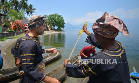 Peserta menunjukan cara melempar jala kepada wisatawan mancanegara saat mengikuti Lomba Manjalo, Festival Danau Maninjau - Kelok 44 di Nagari Maninjau, Agam, Sumatera Barat, Ahad (17/9/2023). Balai Pelestarian Kebudayaan Sumbar menggelar lomba menjala ikan sebagai upaya memunculkan kembali tradisi yang mulai hilang di tepian danau vulkanik itu khususnya menjala dari atas biduk.  