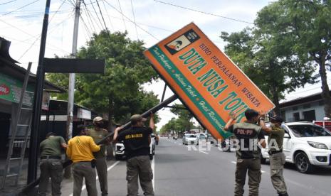 Petugas Satuan Polisi Pamong Praja (Satpol PP) menurunkan papan reklame tak berizin (ilustrasi).