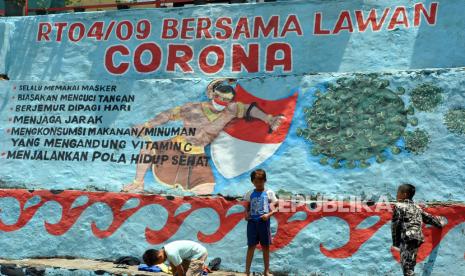 Anak-anak bermain di dekat mural tentang corona di Babakan Pasar, Kota Bogor, Jawa Barat, Kamis (17/9/2020). Mural tersebut berisi imbauan kepada warga untuk selalu menjaga dan mematuhi protokol kesehatan karena wilayah Kota Bogor saat itu masuk salah satu zona merah di Jawa Barat dengan risiko tinggi penyebaran Covid-19.