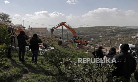  Orang-orang menyaksikan buldoser Israel menghancurkan pemukiman Palestina Nasser Amera di lingkungan Yerusalem Timur di Tsur Baher, Rabu (1/2/2023).  Menteri keamanan nasional Israel Ben Gvir pada 29 Januari memerintahkan untuk mempersiapkan pembongkaran segera bangunan di Yerusalem Timur menyusul serangan terhadap Yerusalem sinagoga 27 Januari.