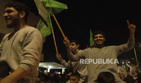 Tahanan Palestina yang dibebaskan oleh otoritas Israel, mengibarkan bendera Palestina dan Hamas sambil digendong setibanya di kota Beitunia, Tepi Barat, Jumat, 24 November 2023.