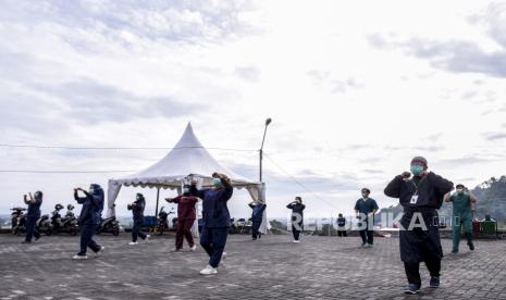 Petugas kesehatan mendampingi pasien Covid-19 untuk melakukan senam pagi di Gedung Balai Latihan Kerja, Manggahang, Kecamatan Baleendah, Kabupaten Bandung, Rabu (30/12). Kementerian Kesehatan mencatat tingkat keterisian ruang isolasi dan gawat darurat atau ICU rumah sakit di beberapa daerah Indonesia melebihi batas aman dengan keterisian di atas 70 persen diantaranya Jakarta, Yogyakarta, Jawa Barat, Jawa Timur dan Jawa Tengah. Foto: Abdan Syakura/Republika