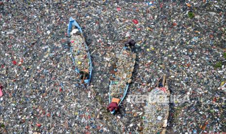 Petugas dengan menggunakan perahu kayu membersihkan sampah plastik yang mengendap di Sungai Citarum di Batujajar, Kabupaten Bandung Barat, Jawa Barat, Rabu (12/6/2024). 