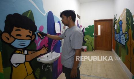 Seorang seniman menyelesaikan pembuatan mural bertema Protokol Kesehatan (Prokes) di TK Kemala Bhayangkari 51, Tangerang, Banten, Rabu (13/10/2021). Pembuatan mural yang dilakukan Polres Metro Tangerang Kota bertujuan untuk mengedukasi anak usia dini tentang pentingnya protokol kesehatan di masa pandemi COVID-19. 