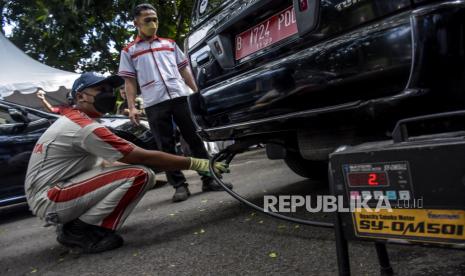 Petugas menguji emisi gas buang pada kendaraan roda empat di halaman Gedung Sate, Jalan Diponegoro, Kota Bandung, Selasa (25/1/2022). Pemerintah Provinsi Jawa Barat melalui Dinas Lingkungan Hidup Provinsi Jawa Barat menggelar uji emisi secara gratis yang bertujuan untuk mengukur besarnya buangan gas emisi kendaraan bermotor serta menekan polusi udara dan mewujudkan kawasan emisi bersih. Foto: Republika/Abdan Syakura