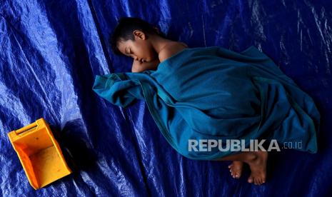 Seorang anak korban banjir luapan Danau Limboto tertidur di lokasi pengungsian Tilango, Kabupaten Gorontalo, Gorontalo, Jumat 19/7/2024). Pemerintah daerah setempat menyediakan lokasi pengungsian serta pasokan bahan makanan berupa beras, minyak goreng, mi instan dan telur, yang telah memasuki hari ke sembilan di pengungsian. 