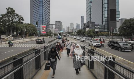 Warga berjalan menuju halte bus TransJakarta di Jalan Jenderal Sudirman, Jakarta.