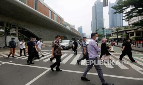 Orang Indonesia berjalan melintasi jalan utama di Jakarta. Peneliti Center for Indonesian Policy Studies (CIPS) Hasran menyatakan kebijakan makro yang diambil Indonesia membuatnya relatif aman dari resesi. Resesi diperkirakan jadi situasi yang baru akan berakhir di akhir 2023 atau di awal 2024.