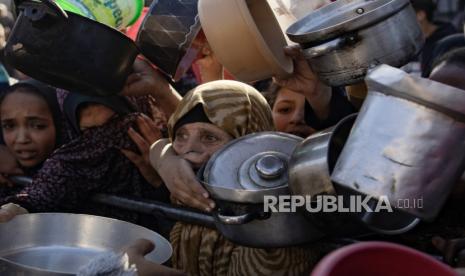 Pengungsi Palestina berkumpul untuk mengumpulkan makanan yang disumbangkan oleh kelompok pemuda amal sebelum sarapan, pada hari kedua bulan suci Ramadhan di Rafah, di selatan Jalur Gaza, (12/3/ 2024).