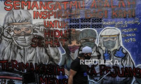 Warga melintas di dekat mural sosialisasi untuk hidup sehat di Rawa Pasung, Bekasi, Jawa Barat.