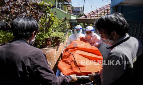 Petugas Public Safety Center 119 (PSC 119) bersama warga mengevakuasi jenazah pasien Covid-19 yang meninggal saat isolasi mandiri (isoman) di rumahnya di Jalan Padasuka, Cibeunying Kidul, Kota Bandung, Rabu (28/7). Berdasarkan hasil data yang dihimpun dari situs laporcovid19.org hingga (28/7) tercatat kasus kematian pasien Covid-19 saat isolasi mandiri dan di luar rumah sakit mencapai 2.705 kasus. Foto: Republika/Abdan Syakura