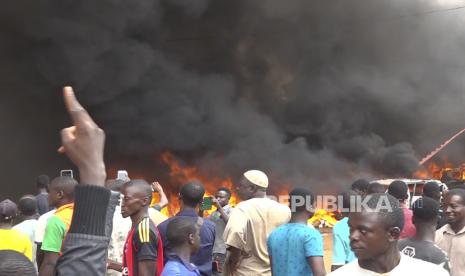 With the headquarters of the ruling party burning in the back, supporters of mutinous soldiers demonstrate in Niamey, Niger, Thursday, July 27 2023. Governing bodies in Africa condemned what they characterized as a coup attempt Wednesday against Niger