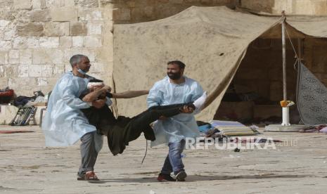 Warga Palestina mengevakuasi seorang pria yang terluka selama bentrokan dengan pasukan keamanan Israel di kompleks Masjid Al-Aqsa di Kota Tua Yerusalem pada hari Senin, 10 Mei 2021. 