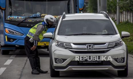 Anggota Satlantas Polresta Bandung memeriksa identitas serta surat keterangan sehat saat operasi penyekatan dan pemeriksaan di Gerbang Keluar Jalan Tol Soreang, Kabupaten Bandung (ilustrasi)