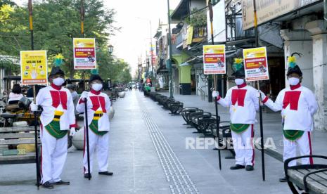 Bregada membawa papan kampanye protokol kesehatan di kawasan wisata Malioboro, Yogyakarta, Ahad (4/7). Gubernur Daerah Istimewa Yogyakarta (DIY) Sri Sultan Hamengku Buwono X memberi instruksi khusus untuk kawasan Malioboro selama PPKM Darurat. Dimana sektor-sektor tertentu di Malioboro harus tutup, di antaranya pedagang kaki lima.