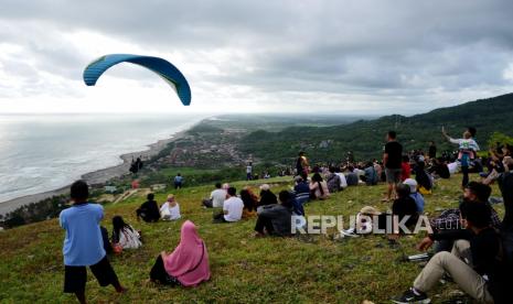 Wisatawan duduk di landasan paralayang Watu Gupit menunggu senja, Purwosari, Gunung Kidul, Yogyakarta. Pemkab Gunung Kidul mengatakan para pelaku wisata harus mematuhi sembilan poin dalam penerapan prokes.