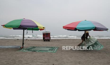 Pedagang membersihkan area di pantai. Ilustrasi