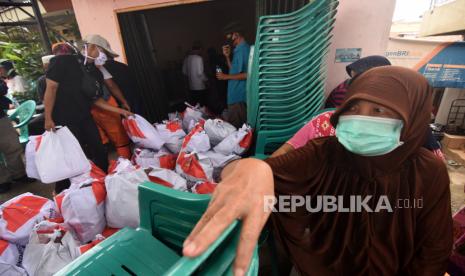 Petugas dibantu warga menurunkan paket sembako yang diberikan Kementerian Sosial (Kemensos). 