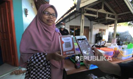 Petugas Bank Indonesia Cirebon menunjukan transaksi melalui aplikasi elektronik di Desa Kenanga, Indramayu, Jawa Barat, Jumat (24/7/2020). Bank Indonesia Cirebon bekerja sama dengan Keluarga Migran Indonesia (KAMI) Jawa Barat memberikan edukasi dan pembuatan Quick Response Indonesia Standard (QRIS) bagi pelaku UMKM untuk mendorong efisiensi transaksi, mempercepat inklusi keuangan, memajukan UMKM dan mendorong pertumbuhan ekonomi. 