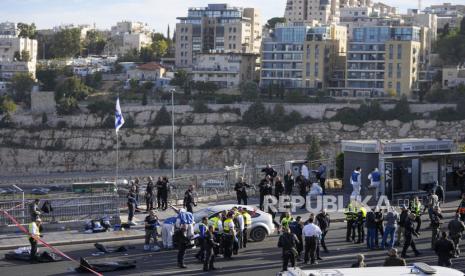 Israeli police officer and volunteers from the Zaka rescue service work at the shooting attack in Jerusalem, Thursday, Nov. 30, 2023. Police said gunmen opened fire Thursday on people waiting for buses and rides where a main highway enters Jerusalem from Tel Aviv. The attack left one dead, one in critical condition and five others wounded, according to Magen David Adom, Israel