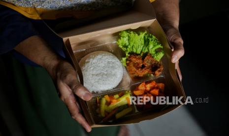 Hadjiah (54) pemilik UMKM Dapoer Mpok Iyah mengemas nasi box pesanan di rumahnya di kawasan Cakung, Jakarta Timur, Selasa (20/2/2024). UMKM berkontribusi 61 persen terhadap PDB.