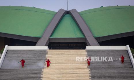 Petugas menyemprotkan cairan disinfektan di area Gedung DPR/MPR RI. Keluarga anggota DPR masuk dalam program vaksinasi di DPR. Vaksinasi anggota dewan sudah dilakukan tapi berjalan secara tertutup.