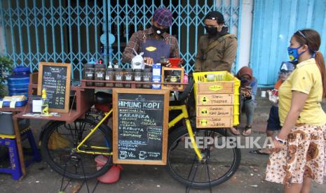 Barista Andik Destanto meracik kopi di kedai kopi yang memanfaatkan sepeda kayuh sebagai kafe mini di jalan Mergosono, Malang, Jawa Timur, Sabtu (18/7/2020). Pemanfaatan sepeda kayuh sebagai kafe mini tersebut sengaja dilakukan Andik untuk sarana pengenalan kopi khas nusantara kepada masyarakat sekaligus menyalurkan hobi bersepeda dengan tetap menerapkan protokol kesehatan guna mencegah penyebaran COVID-19.  