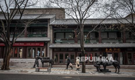 Turis memakai masker berjalan melewati restoran dan toko yang tutup di daerah Tembok Besar Badaling, di Beijing, China, 26 Maret 2020 (dikeluarkan 27 Maret 2020). Kasus corona di China masuki angka nihil, namun China mewaspadai kasus dari warga luar yang masuk ke negaranya.