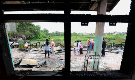 Warga menyaksikan bekas kebakaran di SDN 164 Kota Jambi, Jambi, Ahad (8/5/2022). Kebakaran yang terjadi pada Sabtu (7/5) malam itu menghanguskan lebih dari 70 persen bangunan sekolah. 