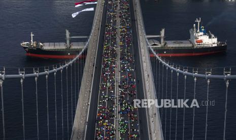  Kapal kargo curah Ikaria Angel, yang berangkat dari pelabuhan Ukraina Chornomorsk, berlayar di bawah jembatan Martir 15 Juli di atas Bosphorus saat para pelari mengambil bagian dalam Marathon di Istanbul, Turki, Ahad, 6 November 2022.