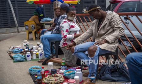  Seorang wanita berkonsultasi dengan dokter tradisional di dekat pangkalan taksi Baragwanath di Soweto, Afrika Selatan, Kamis 2 Desember 2021. Khawatir dengan vaksin, beberapa beralih ke dokter tradisional untuk pengobatan COVID-19. Afrika Selatan meluncurkan kampanye vaksinasi yang dipercepat untuk memerangi peningkatan dramatis dalam kasus COVID-19 yang dikonfirmasi seminggu setelah varian omicron terdeteksi di negara tersebut.