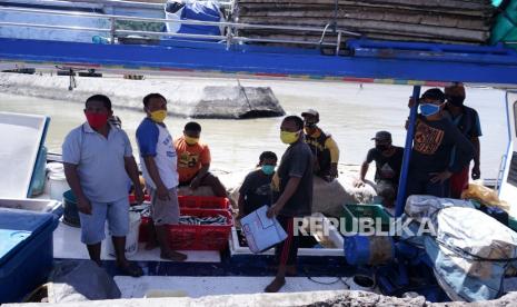 Sejumlah nelayan yang mengenakan masker melakukan bongkar muat ikan di Pangkalan Pendaratan Ikan (PPI) Tenda di Kota Gorontalo, Gorontalo, Kamis (23/4/2020). Pengelola PPI Tenda mewajibkan masyarakat yang masuk ataupun pedagang untuk mengenakan masker dan mencuci tangan saat memasuki kawasan itu sebagai salah satu upaya pencegahan COVID-19 di fasilitas umum