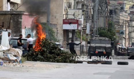 Warga Palestina melempari pasukan Israel dengan batu saat bentrokan di kamp pengungsi Balata dekat kota Nablus di Tepi Barat, Sabtu (13/5/2023). Menurut kementerian kesehatan Palestina, pasukan Israel menggerebek kamp pengungsi Balata pada pagi hari tanggal 13 Mei yang menyebabkan kematian dua orang. orang Palestina.