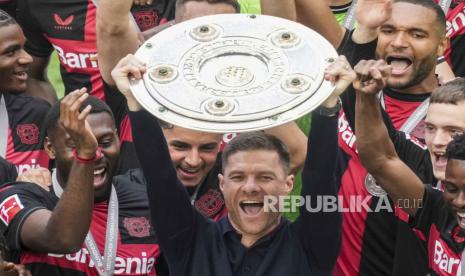 Pelatih Bayer Leverkusen Xabi Alonso memegang trofi juara Bundesliga Jerman.