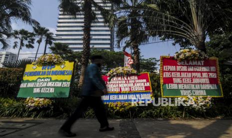 Pejalan kaki melintas di dekat karangan bunga yang terpasang di depan Balai Kota Jakarta, Senin (6/7). Karangan bunga itu merupakan bentuk simbolik kekecewaan dari para orang tua siswa terkait proses Pendaftaran Peserta Didik Baru (PPDB) DKI Jakarta yang dinilai tidak adil. Republika/Putra M. Akbar