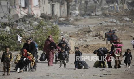 Warga Palestina berjalan setelah menyeberang dari Jalur Gaza utara ke Jalur Gaza selatan saat tank Israel bergerak di sepanjang jalan Salah Al Din, di Jalur Gaza tengah, 26 November 2023. 