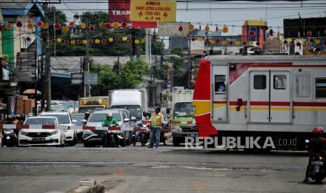 Petugas mengatur lalu lintas di perlintasan KRL di area proyek pembangunan underpass simpang tak sebidang di Jalan Dewi Sartika, Depok,Jawa Barat, Selasa (10/5/2022). Kementerian Pekerjaan Umum dan Perumahan Rakyat (PUPR) menyatakan dibutuhkan biaya sekitar Rp 300 triliun untuk membereskan masalah perlintasan sebidang kereta api. 