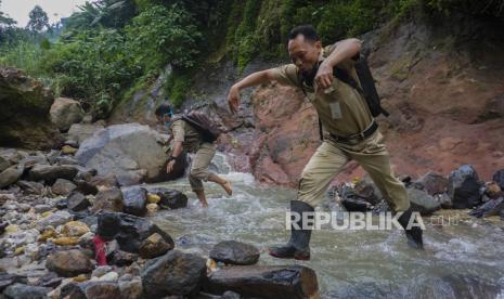 Kepala Sekolah SMP N 4 Bawang Mulud Sugito (kanan) dan guru Wiyata Bhakti melewati aliran sungai di dasar bukit saat mengantar lembar tugas siswa secara langsung ke rumahnya di Pranten, Kecamatan Bawang, Kabupaten Batang, Jawa Tengah.