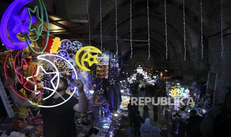 Seorang pedagang Palestina menggantung lampu hias sebagai persiapan untuk bulan suci Ramadhan, di sebuah toko di Kota Tua Yerusalem, Senin, 12 April 2021.