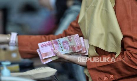 Petugas melayani penukaran uang dolar AS di gerai penukaran mata uang asing.