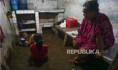 Seorang ibu menyaksikan dua anak bermain air saat banjir merendam rumah mereka di kawasan Kampung Melayu, Jakarta, Ahad (5/11/2023). 